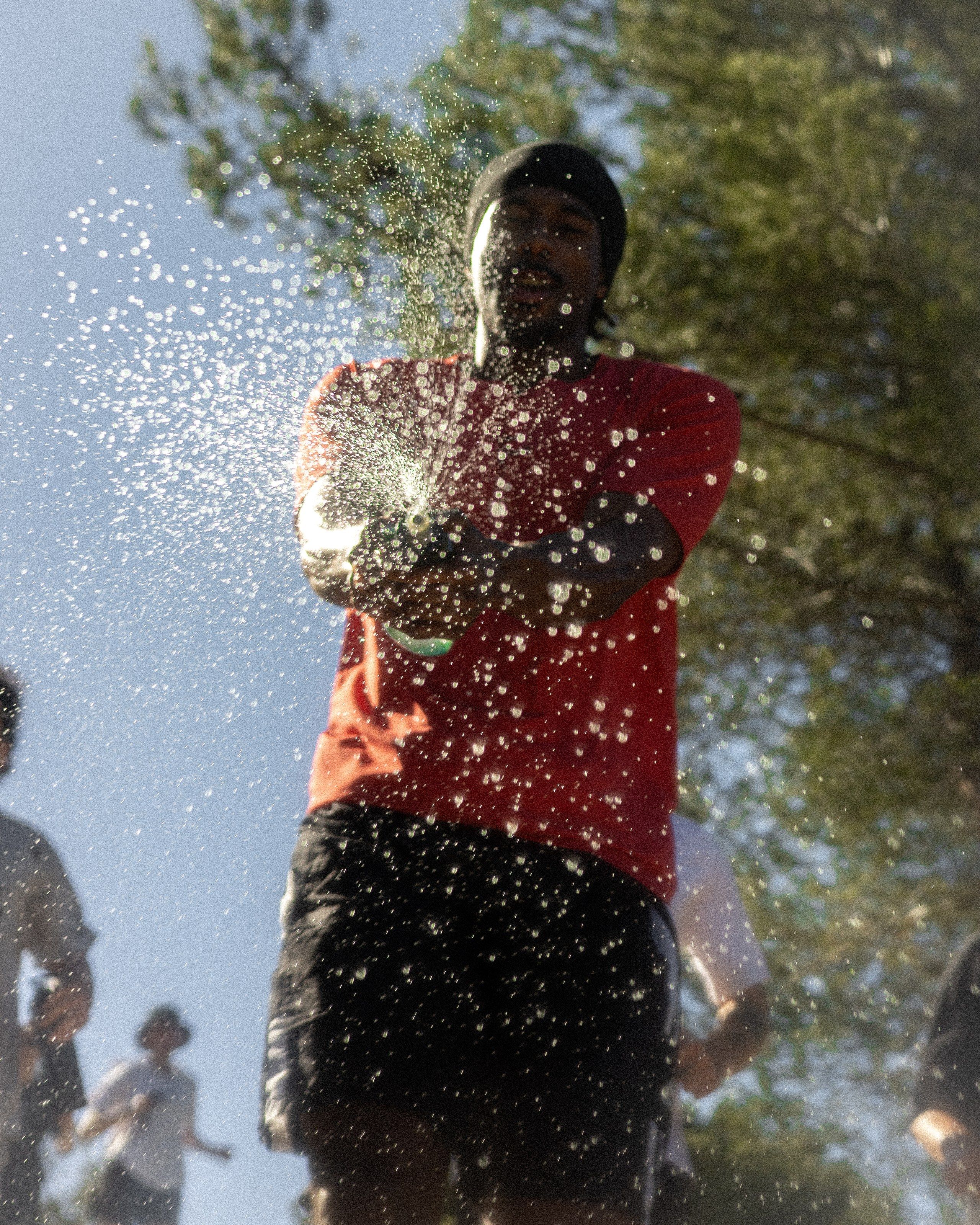 Un coureur sous une gerbe d’eau en plein soleil.