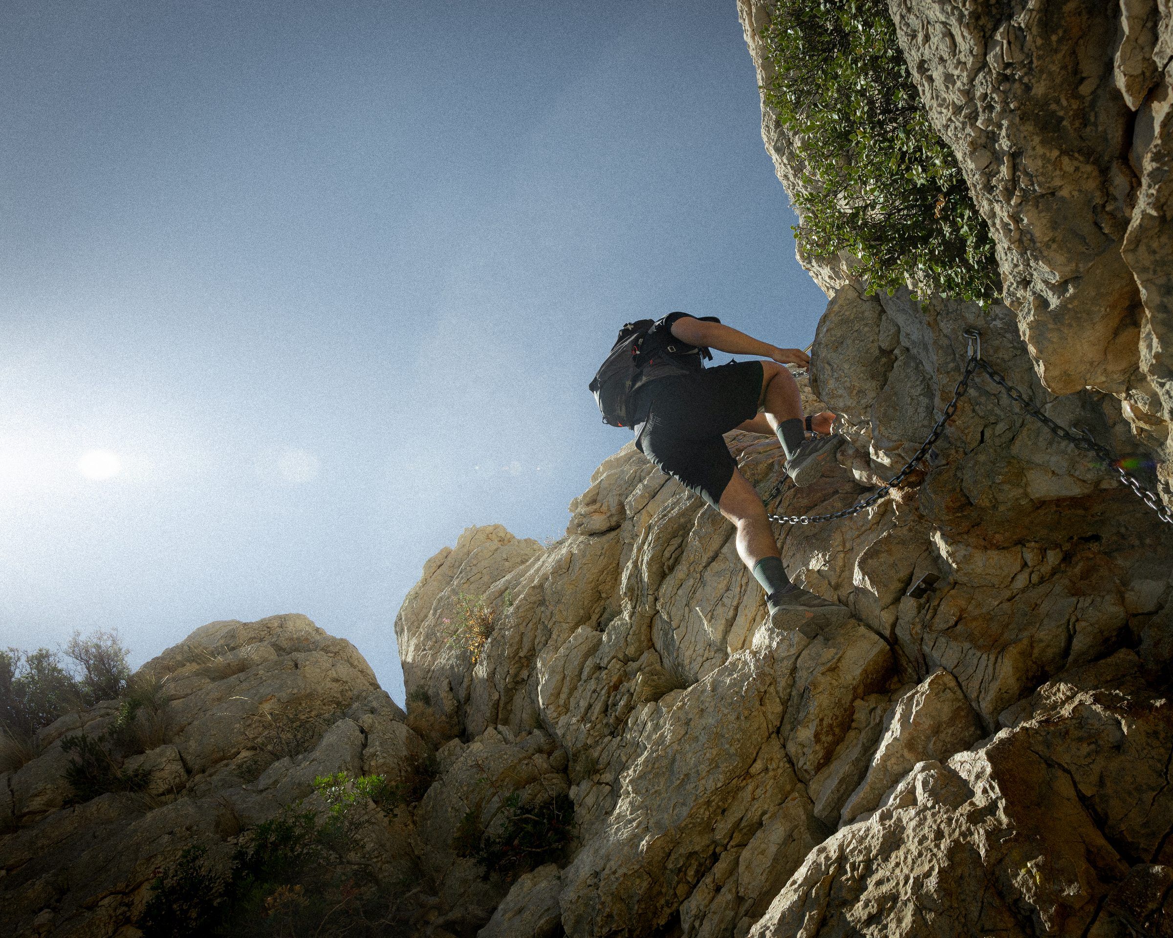 Un randonneur escalade un rocher dans les Calanques.