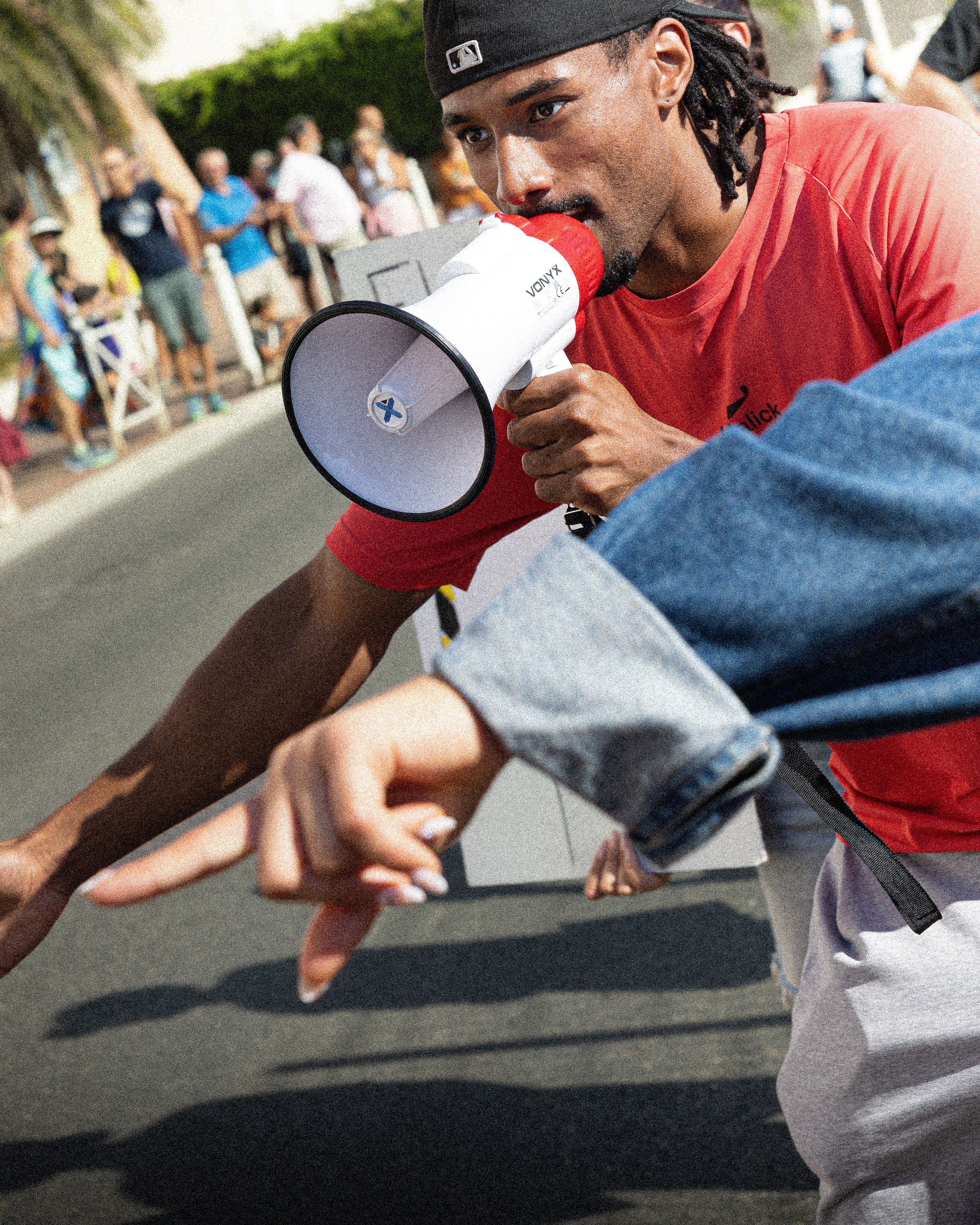 Un membre du club encourage les coureurs au mégaphone, dans la cheer zone de la Carro Carry.