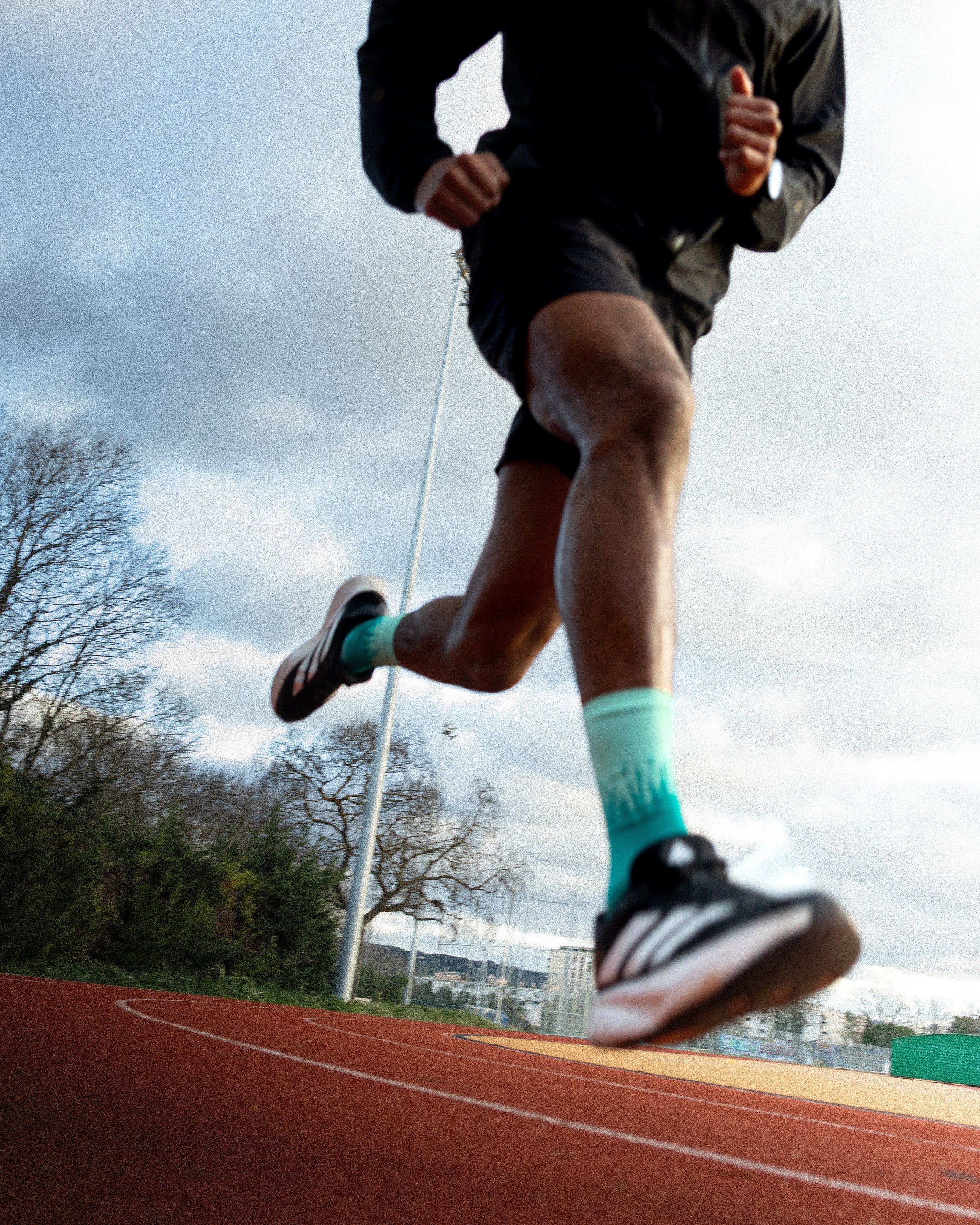 Une foulée sur la piste d’athlétisme, en contre-plongée.
