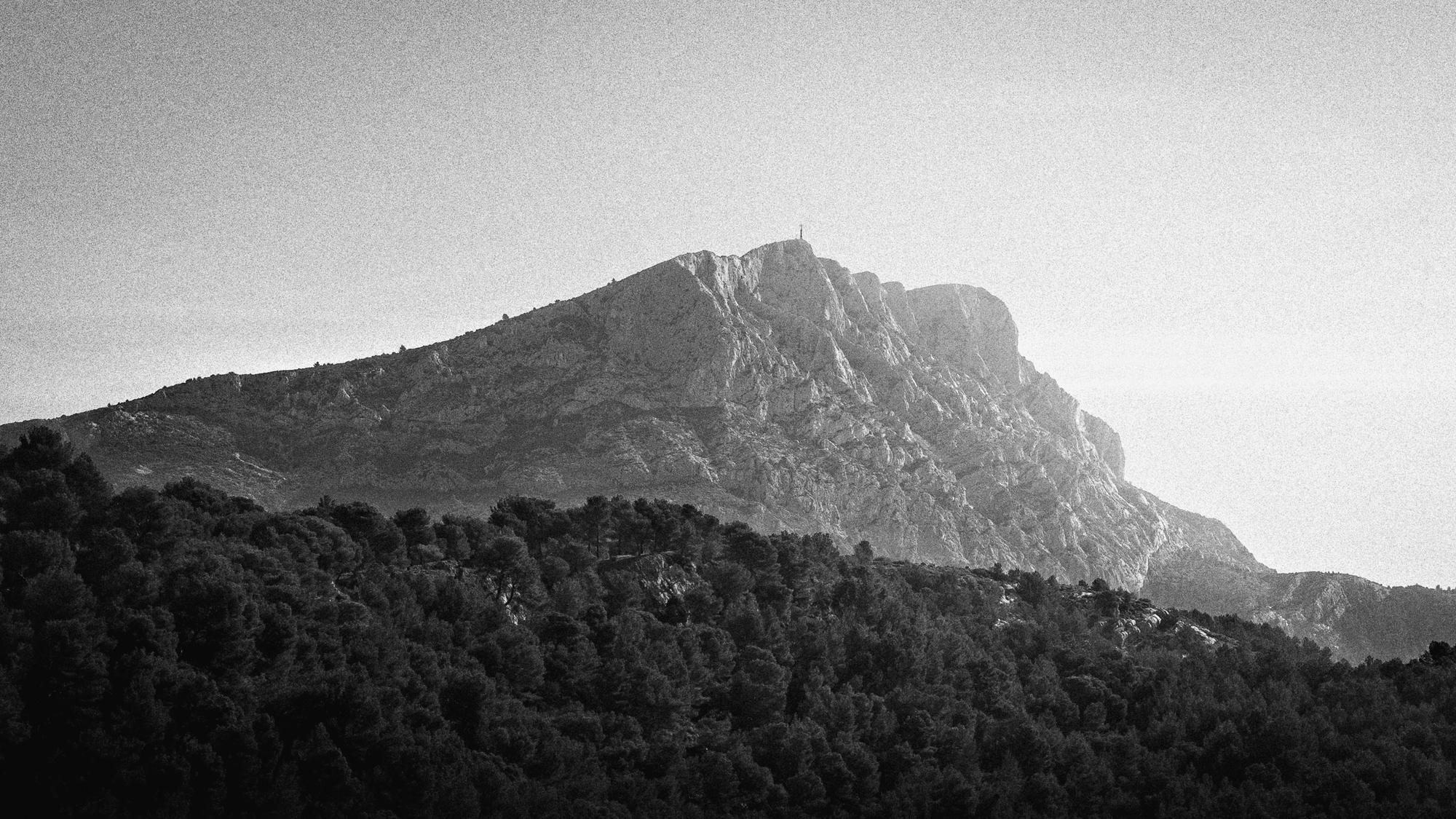 La montagne Sainte-Victoire en entier, sa face calcaire éclairée au-dessus d’une pinède.